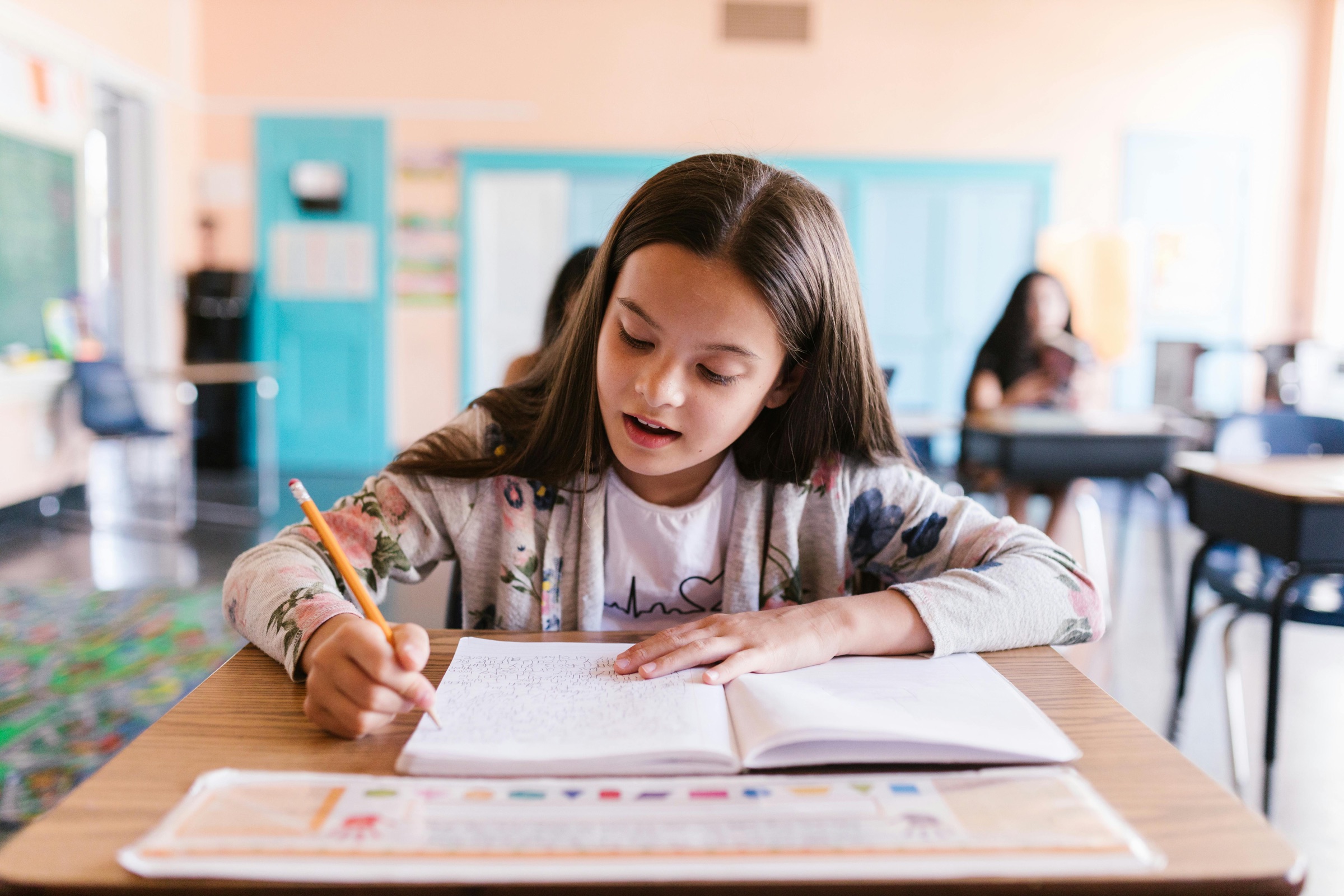 A child writing at a desk in a tuition session